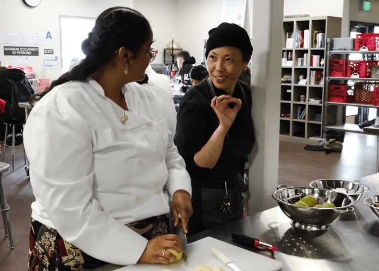 Tina Luu teaches a student how to chop vegetables